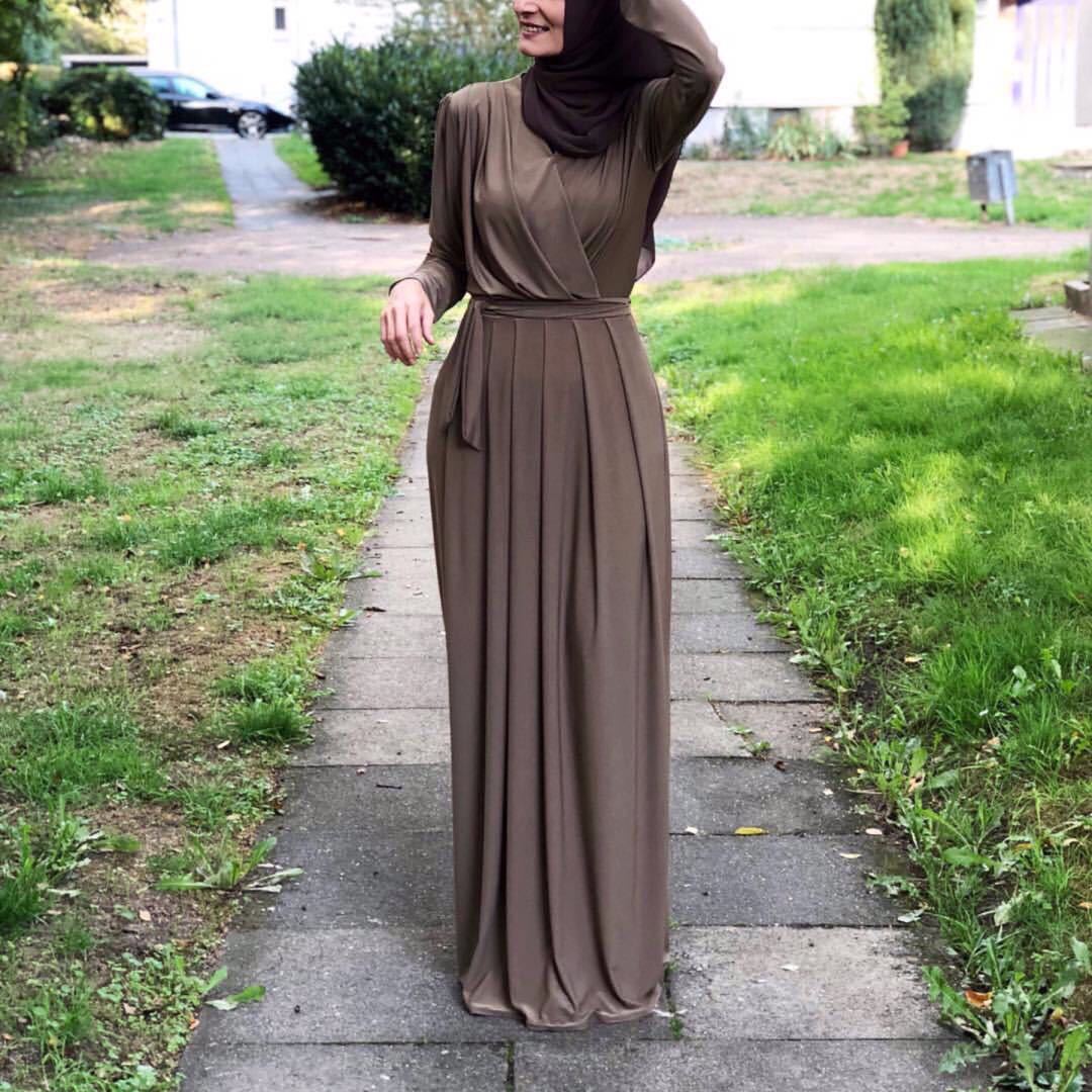 Flowy milk silk abaya dress showcased on a model walking on a path in a garden, exuding elegance and comfort.